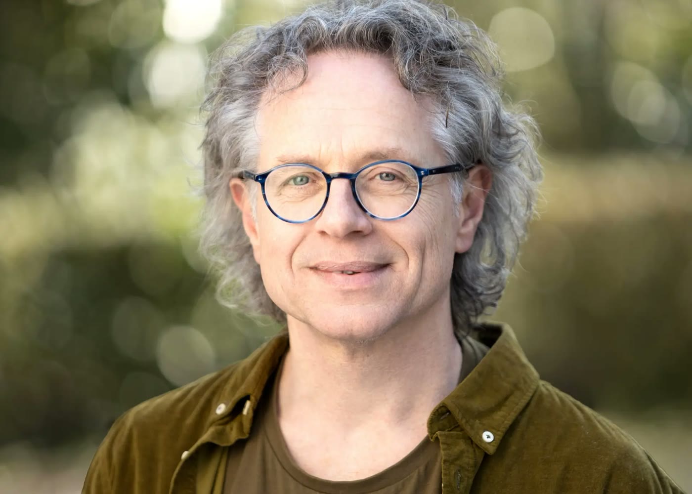 Portret van Cor van der Wekken buiten, met een zachte groene achtergrond